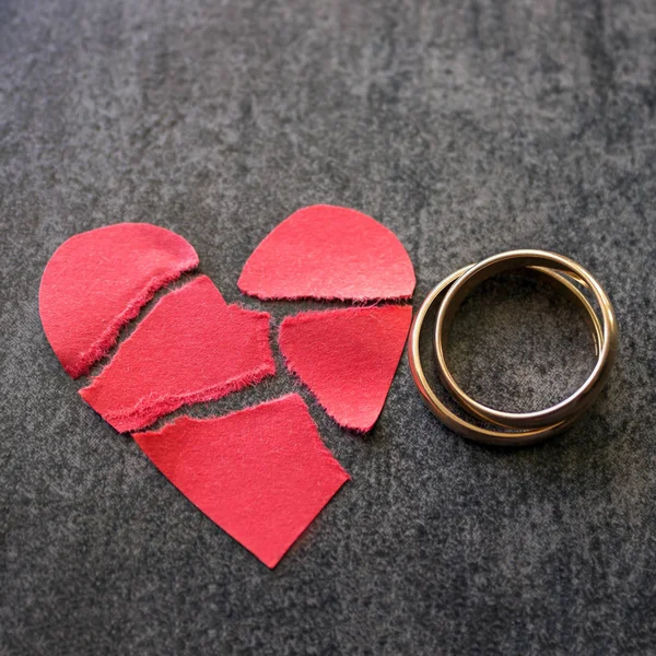 Anillos de boda y corazón rojo roto. Fondo negro. El cono — Foto de Stock