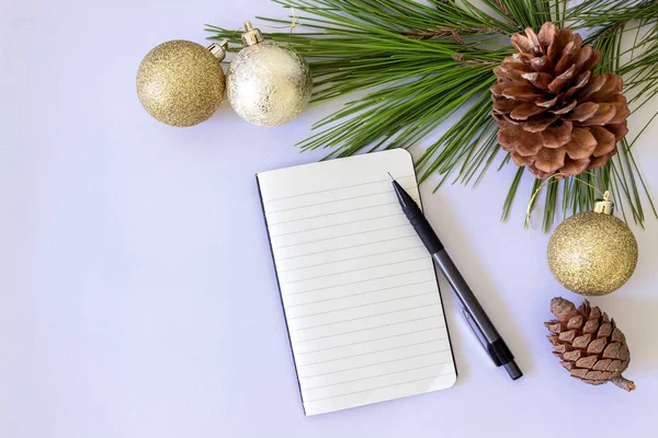 Yeni yıl için hazırlanıyor. Beyaz arka planda kalem ve Noel topları ile boş not defteri. 