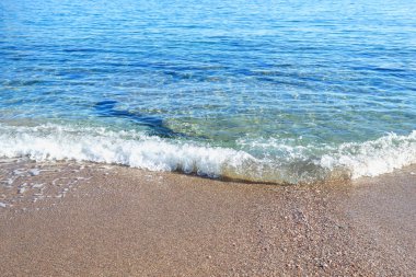 Güneşli kumlu bir plaj tatil üzerinde yaz tatil dinlenme köpük mavi denizde dalgalarla.