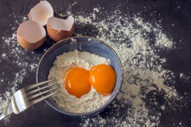 Yumurta ve un mavi kapta. Ev pişirme için malzemeler.