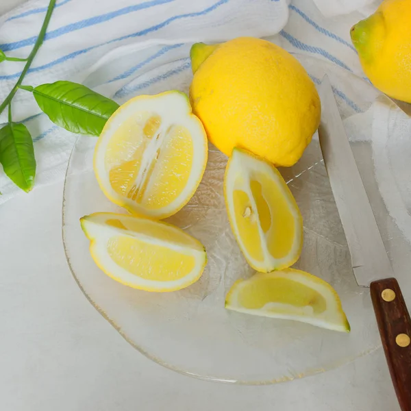 Saftige Zitronen und Scheiben in transparenter Schale. — Stockfoto