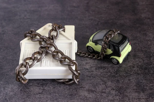 Small white house, car and a decorative chain on a dark background.