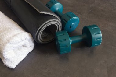 Siyah yoga mat, iki Halter ve beyaz bir havlu karanlık bir taş yüzeye yalan.