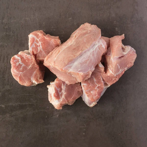Carne crua fresca está na superfície de uma pedra escura . — Fotografia de Stock
