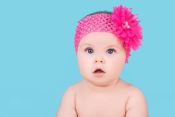 Bebê bonito com flor de arco rosa na cabeça, isolado em azul — Fotografia de Stock