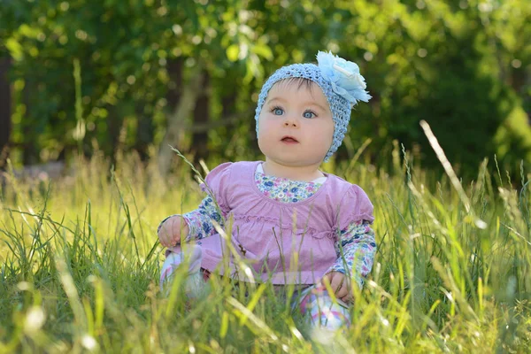 Baby girl sitting on a green grass on the nature in the park — Stock Photo, Image