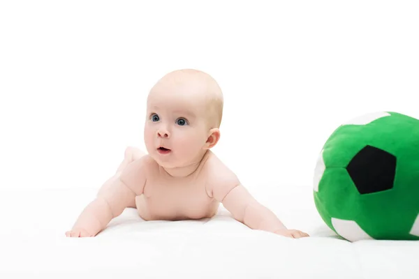 Baby boy or girl lying down on his belly and playing with soccer — Stock Photo, Image
