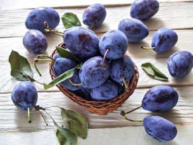 Hasır sepet içinde taze büyük Erik bir ahşap arka plan üzerinde yalan