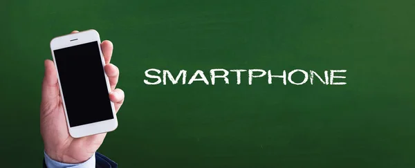 Smartphone na mão na frente de quadro-negro — Fotografia de Stock