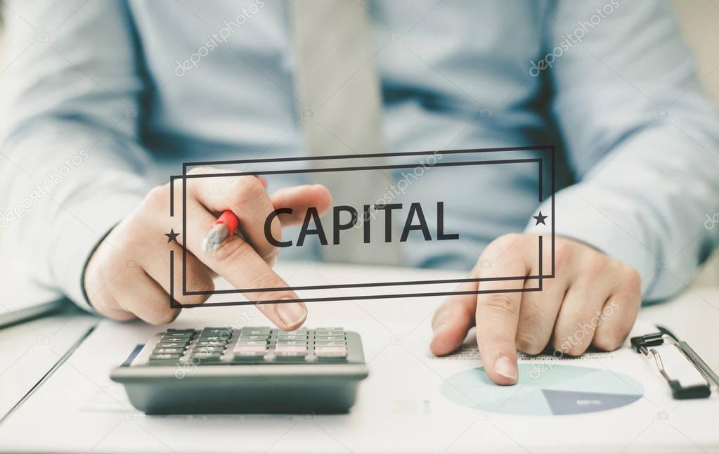 Man using calculator on background FINANCE CONCEPT: CAPITAL
