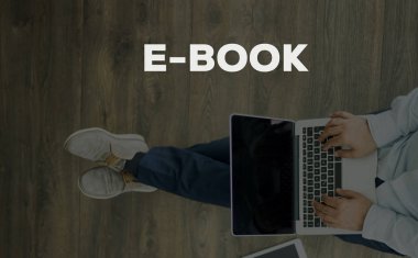 Genç adam dizüstü bilgisayarla yerde oturuyor.