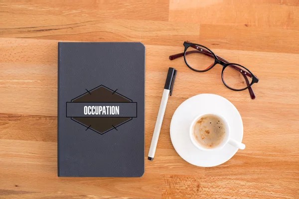 Cuaderno, taza y vasos en el escritorio . — Foto de Stock