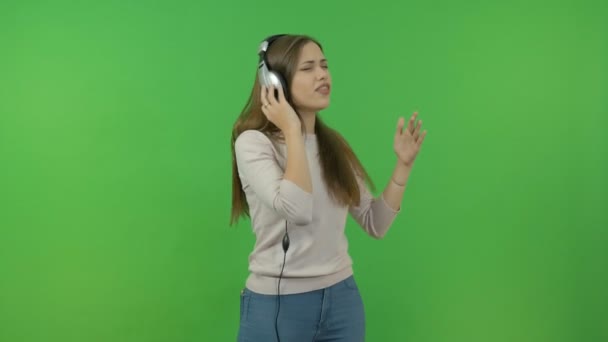 Красивая девушка с длинными волосами слушает музыку через