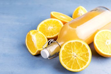 Mavi zemin üzerine portakal ile taze portakal suyu.   