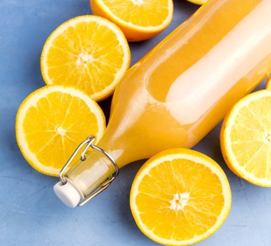 Mavi zemin üzerine portakal ile taze portakal suyu.   