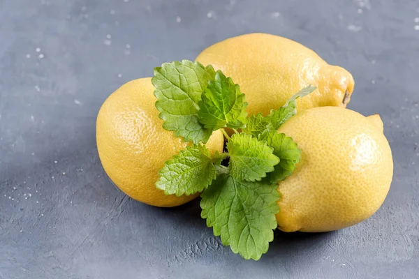 회색 배경에 노란색 신선한 감귤 류의 민트 잎 절단 보드에 레몬 — 스톡 사진