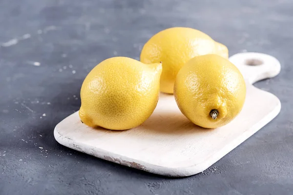 Citroner på skärbräda på grå bakgrund färsk gul citrus — Stockfoto