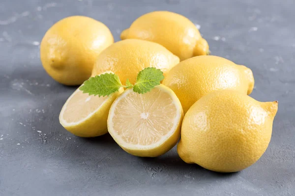 Citroner på skärbräda på grå bakgrund färsk gul citrus mynta blad — Stockfoto