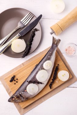 Soğan ve ahşap masa üzerine biber ile lezzetli tuzlanmış ringa ahşap arka plan rustik tarzı üstten görünüm dikey beyaz