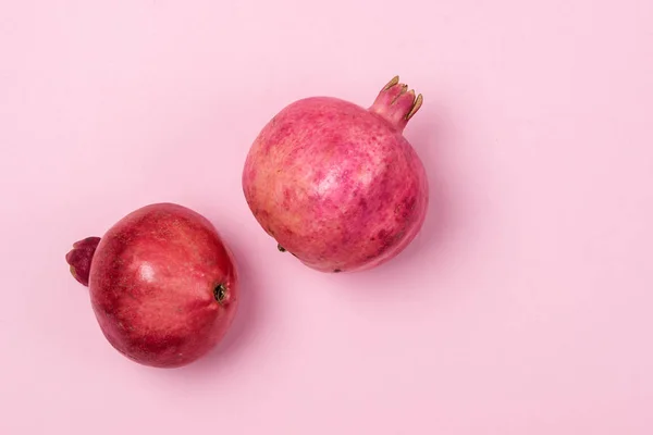 두 개의 맛있는 싱싱 한 석류는 가로로 떨어져 있는 핑크 색 배경입니다. — 스톡 사진