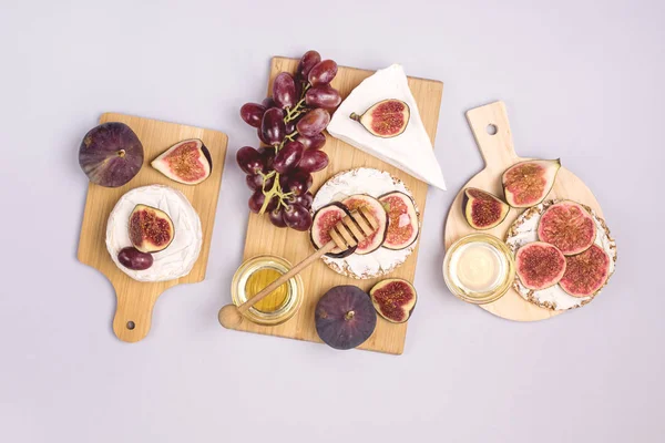 Tres tablas de corte de madera con higos brie de queso miel y uvas rosadas Vista superior Flat Lay fondo azul —  Fotos de Stock