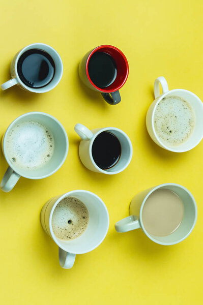 Assortment of Coffee Cups with Coffee Espresso Capuccino Coffee with Milk on a Yellow Paper Background Flat Lay Top View Vertical