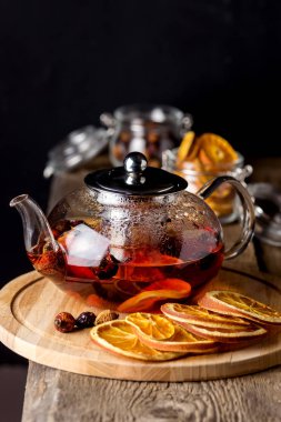 Tahta tepside kurutulmuş portakal ve böğürtlenli çaydanlık Kurumuş Citrus Tahta Arka plan Sıcak Kış veya Sonbahar İçkisi Dikey