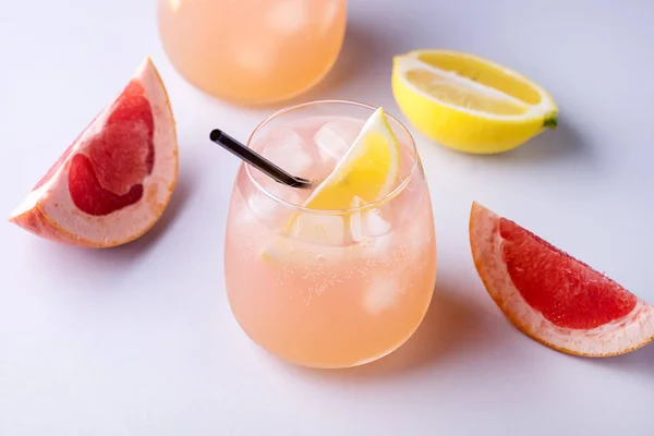 Dos vasos de cóctel con pomelo y limón Bebida de cítricos o limonada con cubitos de hielo y fondo azul pajizo — Foto de Stock
