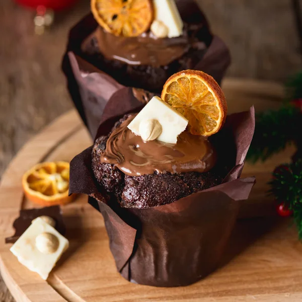 Close Up Due gustosi muffin al cioccolato fatti in casa decorati con patatine agli agrumi e cioccolato bianco su vassoio di legno Natale Dessert Food Vertical — Foto Stock