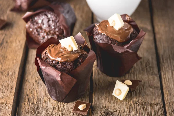 Tre gustosi muffin al cioccolato decorati con cioccolato su sfondo di legno tazza bianca di cococa con foto scura verticale — Foto Stock