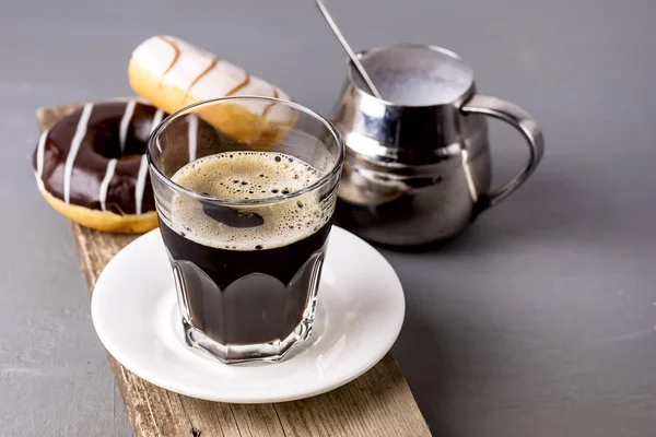 Glas av svart americano kaffe och god choklad och vaniljmunkar på träbricka grå bakgrund morgon frukost livsstil Kopiera utrymme — Stockfoto