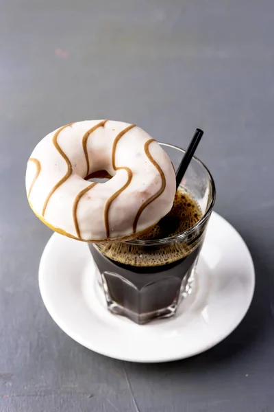 Glas Kaffee und leckerer Donut mit Schokoladenglasur über leckerem Dessert-Snack senkrecht — Stockfoto