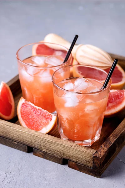 Dos vasos de pomelo sabroso bebida fría o cóctel en bandeja de madera refresco bebida gris fondo zumo de pomelo frío — Foto de Stock