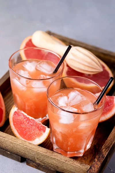 Dos vasos de pomelo sabroso bebida fría o cóctel en bandeja de madera refresco bebida gris fondo zumo de pomelo frío — Foto de Stock