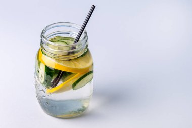 Organik meyve ve sebze salatalıkları ve limon sağlıklı Detox içecek alanlarıyla yapılmış taze erimiş suyla dolu cam kavanozlar.