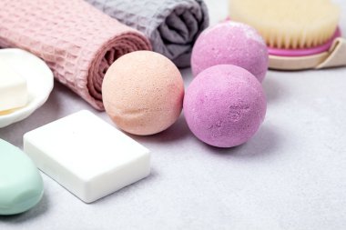 SPA Pembe Hayat Pembesi ve Açık Turuncu Banyo Bombaları Açık Gri Arkaplandaki Kozmetik Yağlar Yıkama Fırçası Gri ve Pembe Havlu Güzellik Konsepti