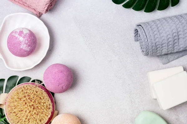 SPA Pembe Hayat Pembesi ve Açık Turuncu Banyo Bombaları Açık Gri Arkaplandaki Kozmetik Yağlar Yıkama Fırçası Gri ve Pembe Havlu Güzellik Konsepti