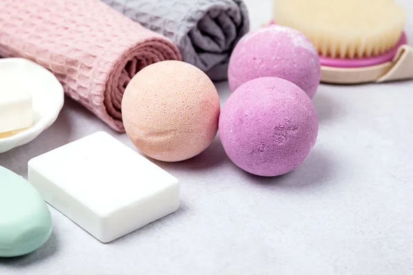 SPA Pembe Hayat Pembesi ve Açık Turuncu Banyo Bombaları Açık Gri Arkaplandaki Kozmetik Yağlar Yıkama Fırçası Gri ve Pembe Havlu Güzellik Konsepti