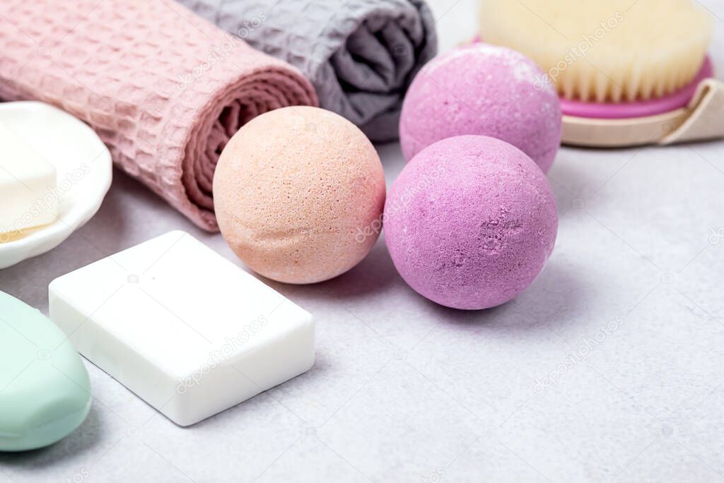 SPA Still Life Background Pink and Light Orange Bath Bombs Soaps Cosmetic Oil on Light Gray Background Washing Brush Gray and Pink Towel Spa Beauty Concept Top View Flat Lay