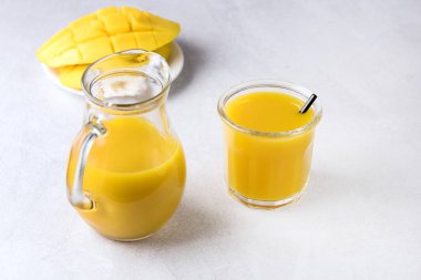 Lezzetli Lezzetli Mango Suyu ve Açık Gri Arka plan Vitamini ve Sağlıklı İçecek Üzerine Olgun Dilimlenmiş Mango