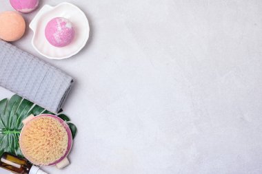 SPA Pembe Hayat Pembesi ve Açık Turuncu Banyo Bombaları Açık Gri Arkaplandaki Kozmetik Yağlar Yıkama Fırçası Gri ve Pembe Havlu Güzellik Konsepti