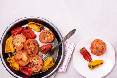 Büyük siyah tabak ve hafif arkaplanda ızgara sebze tabağı fırınlanmış domatesler ve biberler sağlıklı beslenme yemeği veya öğle yemeği.