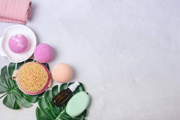 SPA Pembe Hayat Pembesi ve Açık Turuncu Banyo Bombaları Açık Gri Arkaplandaki Kozmetik Yağlar Yıkama Fırçası Gri ve Pembe Havlu Güzellik Konsepti