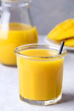 Dilimlenmiş ve tüm mango meyveli bir bardak lezzetli mango suyu. Sağlıklı ve dikey.