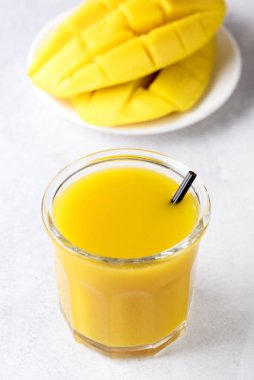 Dilimlenmiş ve tüm mango meyveli bir bardak lezzetli mango suyu. Sağlıklı ve dikey.