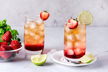 Bir bardak çilek ve limonlu buzlu çay. Sağlıklı yaz içeceği. Hafif gri arka plan.