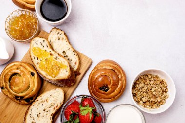 Lezzetli Kahvaltı Kuru Üzümlü Taze Çörekler ve Tarçın Taze Ev Yapımı Ekmek Fincanı Kremalı Süt Kremalı Çilek ve Portakal Reçelli Cam kâse Üst Görünüm Müsli