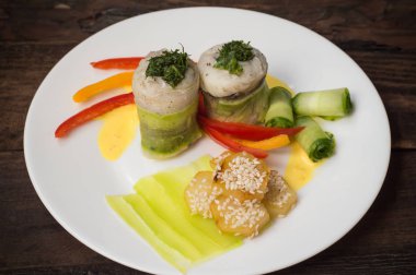 Balık biber ve salatalık dilimleri ile susam serpilir kavrulmuş patates ile kabak içinde sarılı rulo. Ahşap rustik arka plan. Üstten Görünüm. Yakın çekim