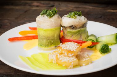 Balık biber ve salatalık dilimleri ile susam serpilir kavrulmuş patates ile kabak içinde sarılı rulo. Ahşap rustik arka plan. Üstten Görünüm. Yakın çekim