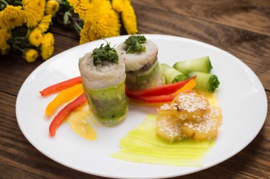 Balık biber ve salatalık dilimleri ile susam serpilir kavrulmuş patates ile kabak içinde sarılı rulo. Ahşap rustik arka plan. Üstten Görünüm. Yakın çekim